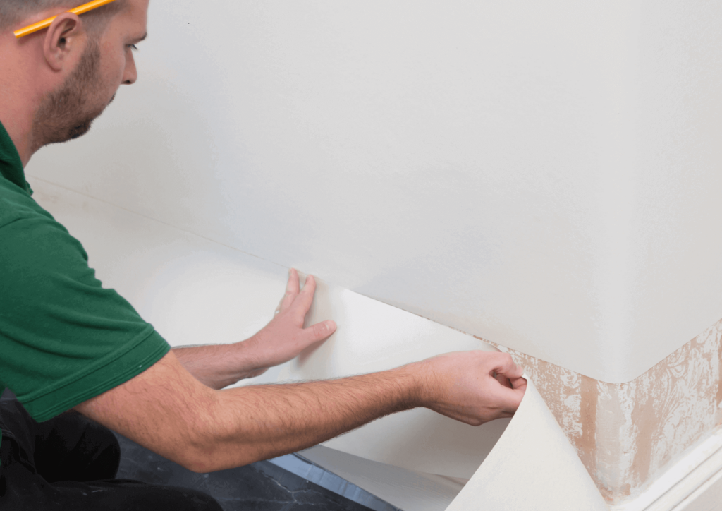 a man working on sticking the wallpaper to the wall