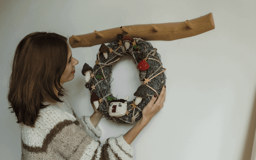A woman hanging a wreath on the wall with a decorative wall hook made of wood