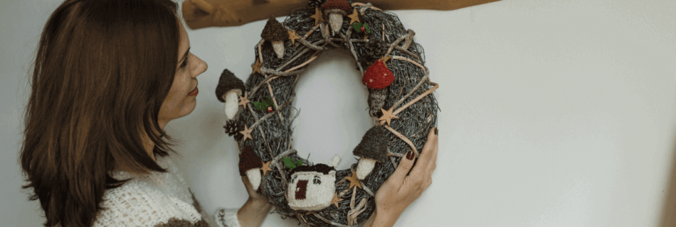A woman hanging a wreath on the wall with a decorative wall hook made of wood