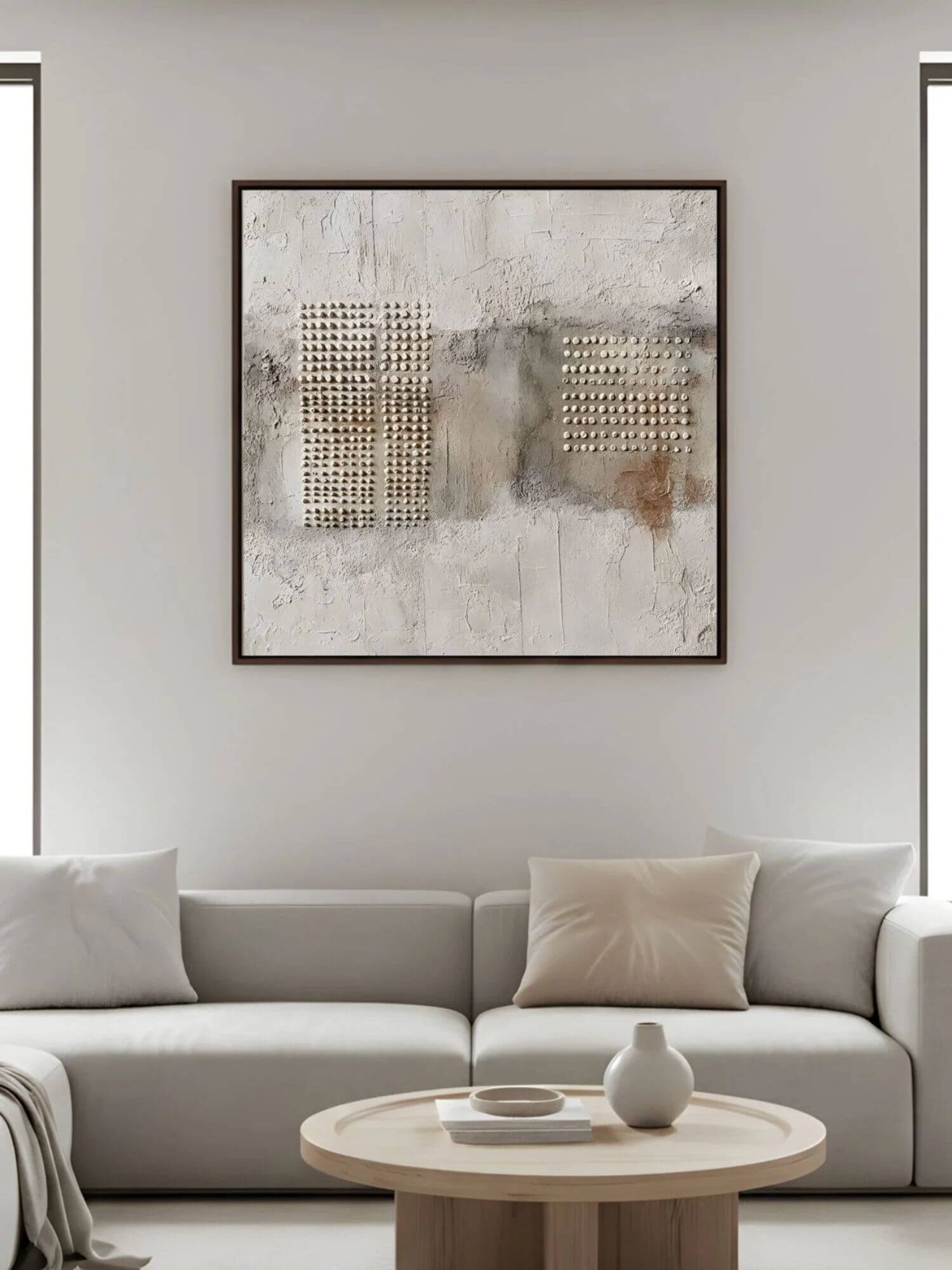 Minimal living room with square textured wabi-sabi artwork above a neutral sofa.