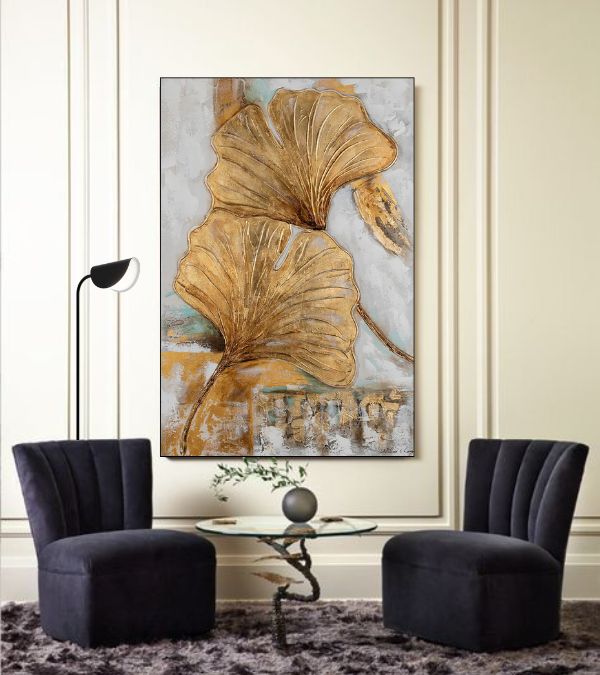 Modern minimalist living room featuring a black armchair, golden leaf wall art, white walls, and a sleek wooden side table.